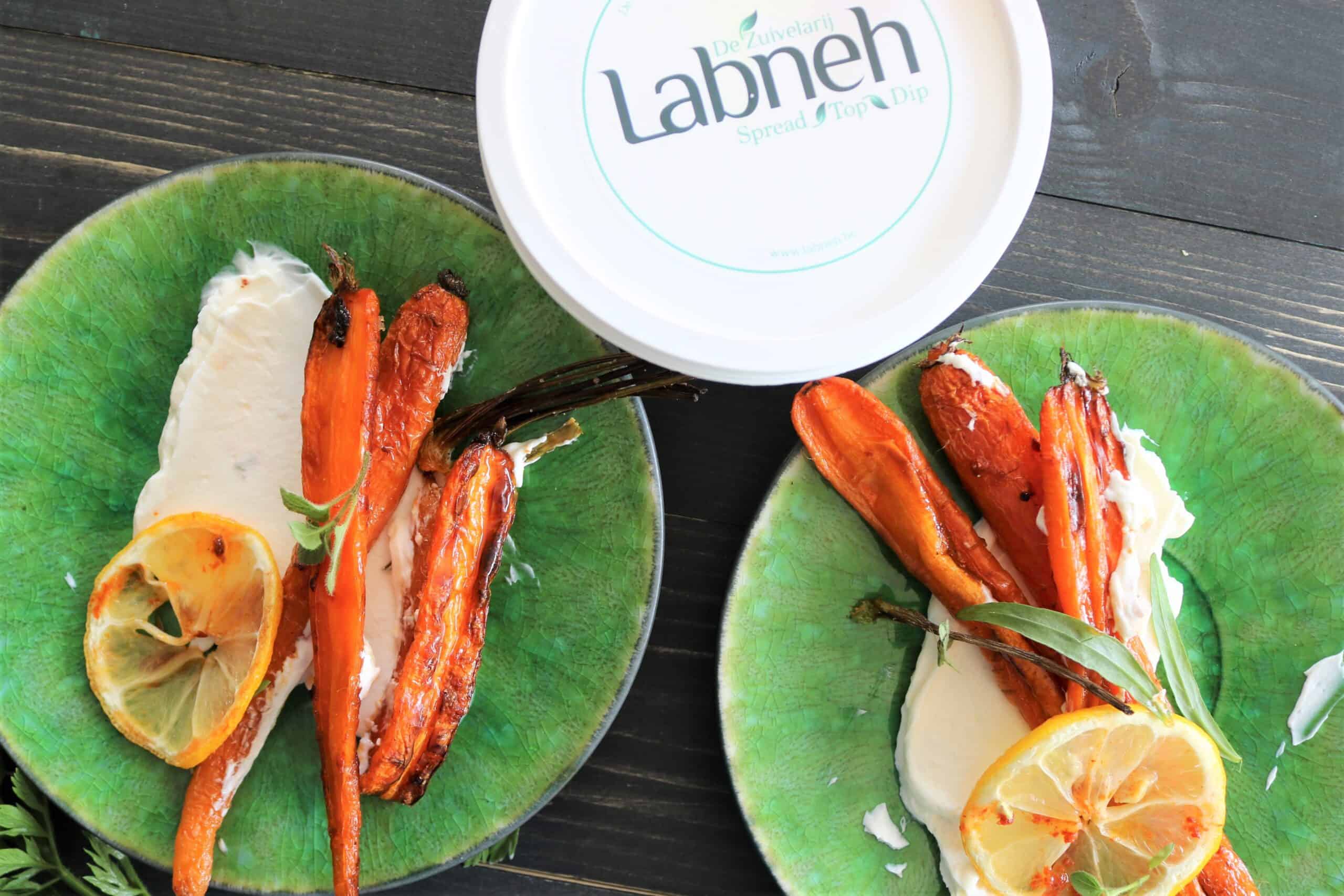 Roasted carrots on a green small plate with labneh and lemon.