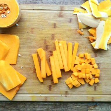 Vers gesneden kaas en pompoen op houten snijplank.