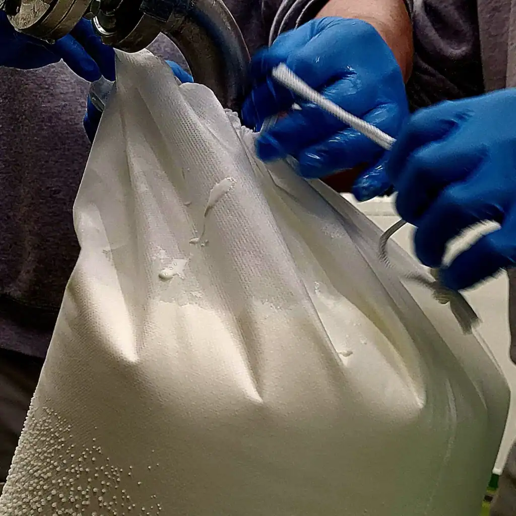 Handen die labneh maken met blauwe handschoenen en een spuitzak.