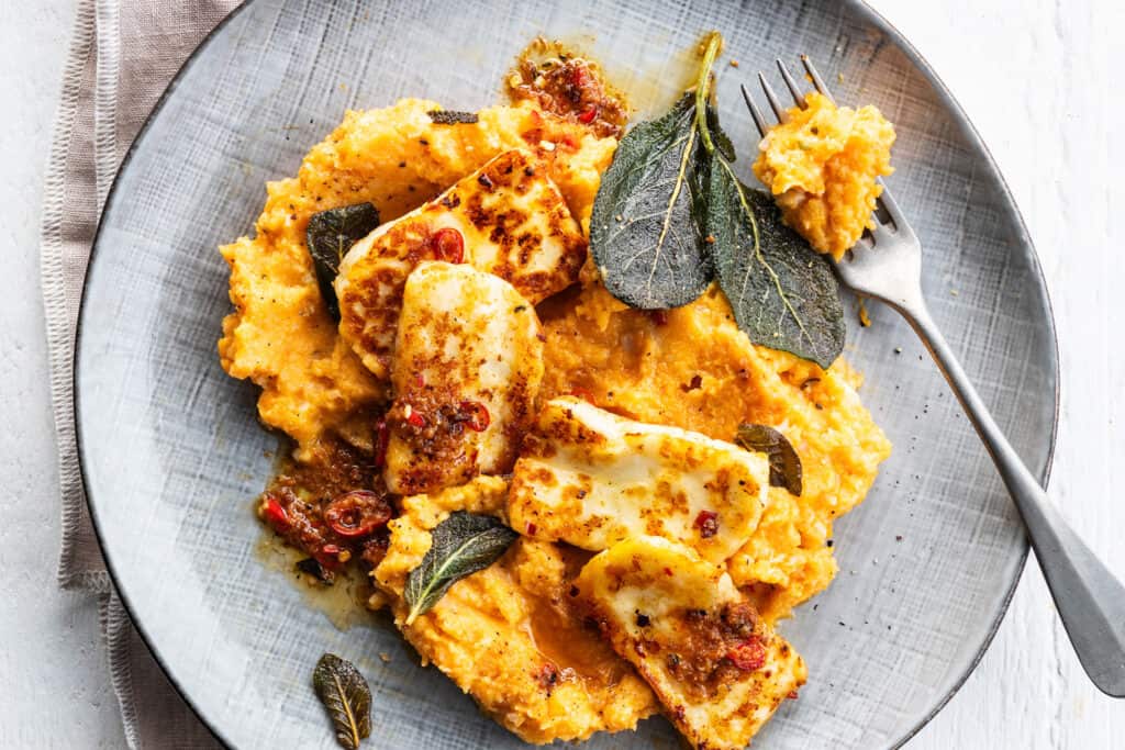 Geroosterde Berloumi kaas met kruiden en tomatensaus op een bord.
