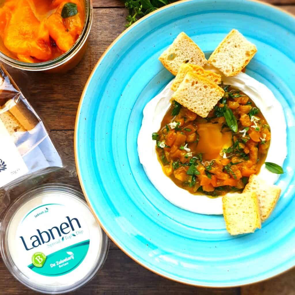 Gekonfijte paprika met zachte zuiveldip en toast, perfect voor een smakelijk hapje.