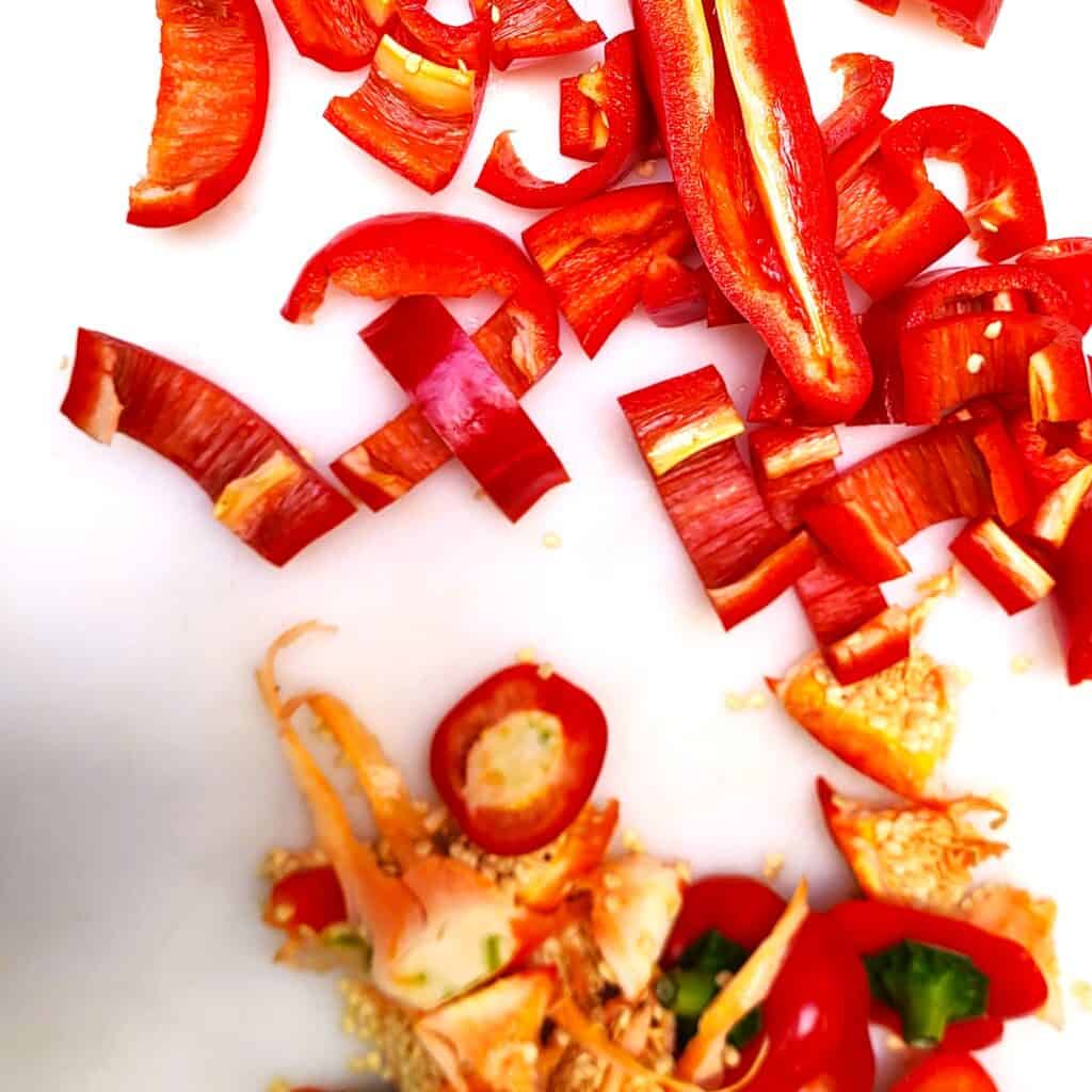 Gekonfijte rode paprika stukjes op een witte achtergrond.